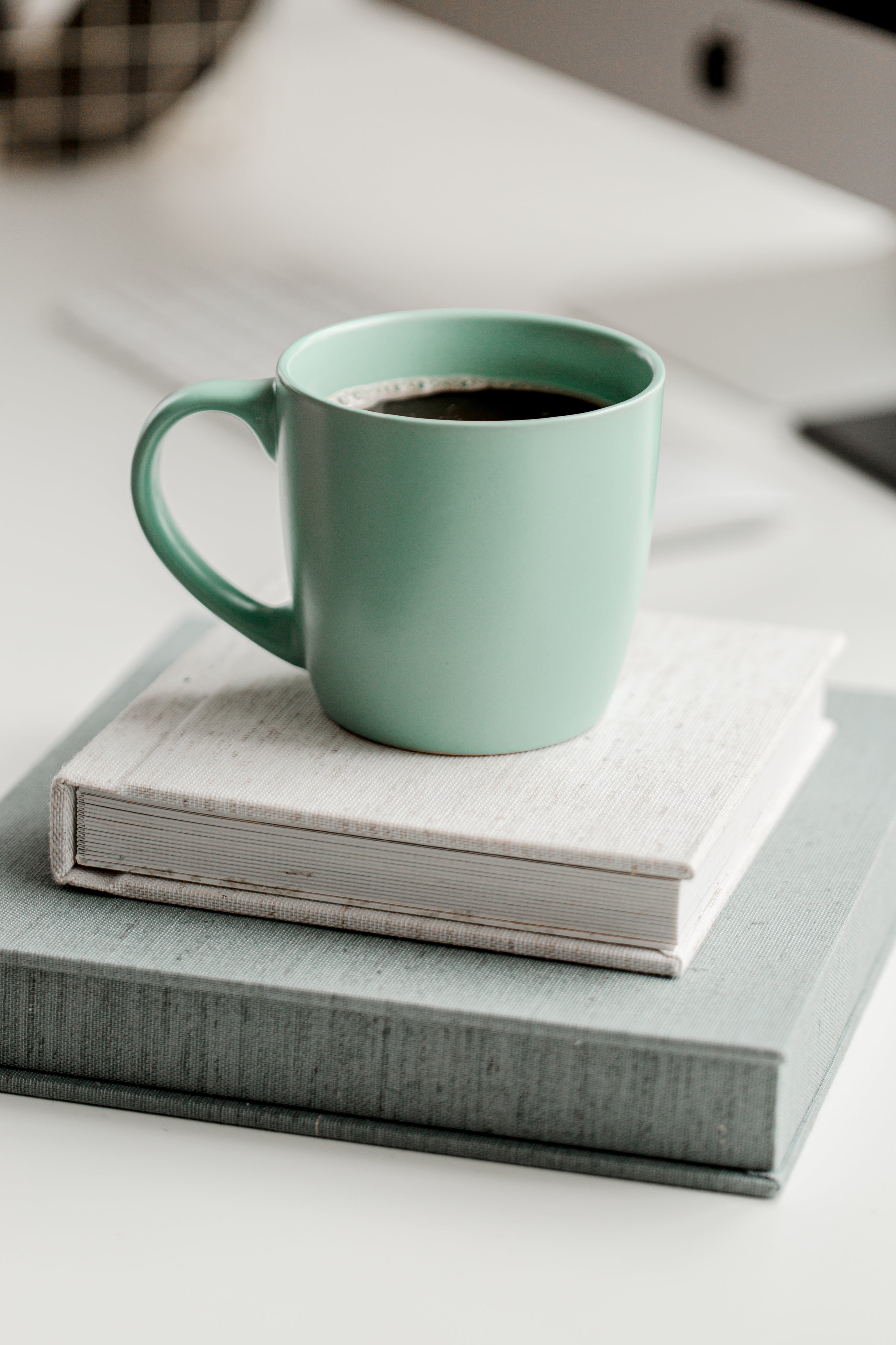 mint-green-mug-full-of-black-coffee-on-top-of-books.jpg